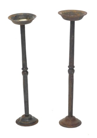 A near pair of wrought iron candle stands, each of ecclesiastical form, on a domed foot, 55cm and 57cm high.