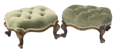 A pair of Victorian walnut footstools, each with a green fabric buttoned top, on cabriole legs.