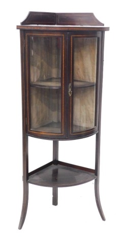 An Edwardian mahogany and chequer banded standing bow fronted corner display cabinet, with a raised back above two glazed doors, and an under tier, on splayed legs, 132cm high, 54cm wide.