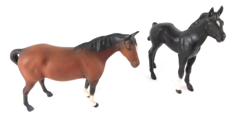 A Beswick pottery matt finish pony, in brown with front white legs, 13cm high, and a black matt finish pottery figure of a foal. (2)