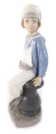 A Lladro pottery figure of a child holding a toy yacht, printed and impressed marks beneath, 26cm high.