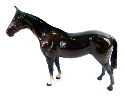 A Beswick pottery figure of a bay horse, with white front legs, printed marks beneath, 20cm high.