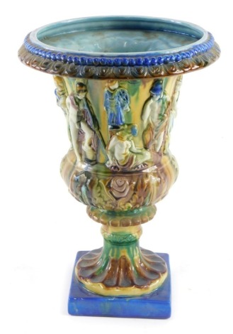 A 19thC style Majolica urn, raised with classical figures, on an inverted stem and square foot, profusely decorated predominately in brown, green, yellow, and blue, unmarked, 35cm high.