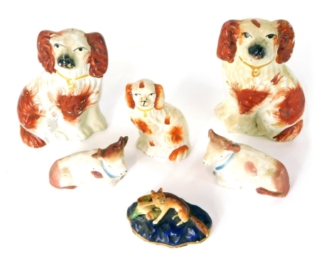 A pair of miniature Staffordshire pottery spaniels, each with gilt collars, in red and white colourway, 14cm high, two Continental porcelain recumbent cow ornaments, single Staffordshire dog, and a 19thC fox group, with paw on shell. (a quantity)