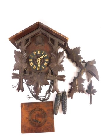 A 20thC Black Forest style cuckoo clock, with 11cm diameter chapter ring, raised with Roman numerals beneath cuckoo, flanked by carved leaves, 37cm high with two weights.