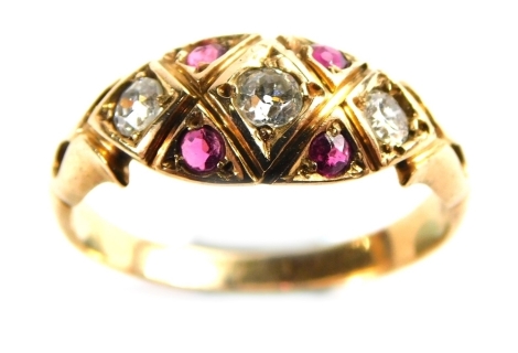 An Edwardian ruby and diamond dress ring, the central marquise shaped panel set with round brilliant cut diamonds and four rubies, each in triangle section, with pierced design shoulders, on a yellow metal band, rose gold, unmarked, L½, 2.4g all in.