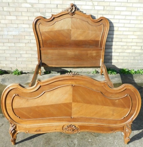 A 19thC French walnut bed, with shaped headboard centred by scrolls and a shell, with further acanthus leaves, with a scroll outline, on turned feet, with similar footboard surmounted by a shell, with heavy supports, the headboard 138cm high, 139cm wide, 