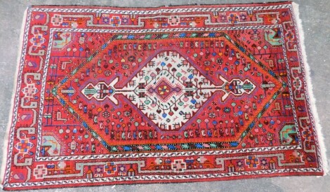 A Turkish rug with a central pole medallion on a red ground, decorated overall with multicoloured geometric shapes, to include horse, botei etc., one wide border, 222cm x 132cm.