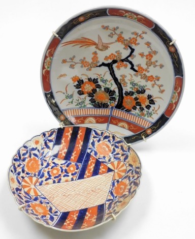 A 20thC Imari charger, decorated with flowering shrub and prunus decoration and a bird, impressed seal mark to underside, 37cm diameter, together with an Imari scalloped dish painted with flower heads and geometric decoration, 31cm diameter, (2).