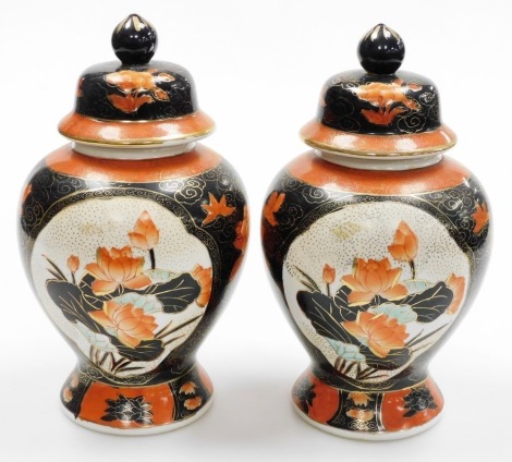 A pair of Chinese famille noir porcelain jars and covers, painted with floral designs in iron red, black and gilt, red seal mark to underside, 28cm high.