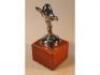 A Spirit of Ecstasy Rolls Royce car mascot mounted on a wooden plinth