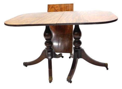 A Regency style mahogany twin pedestal dining table, the top with a reeded border, on twin turned supports with tripod base and brass castors, two loose leaves, 76cm high, 177cm wide, 87cm deep.