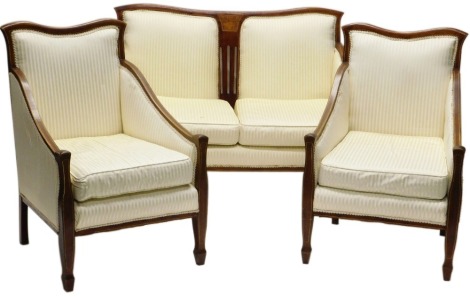 An Edwardian mahogany and marquetry three piece salon suite, with padded back, sides and seat upholstered in gold striped fabric, on boxwood strung square tapering legs, comprising two seat sofa and two chairs.