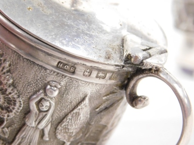 A 20thC Indian silver three piece cruet, comprising lidded mustard pot and two open salts, each piece embossed with figures and buildings in a rural setting, blue glass liners, later hallmarked, Henry Charles Freeman and J.B. & Co., Birmingham 1911 and 19 - 2