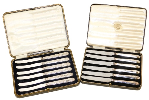 A set of six Edward VII silver handled cake knives, each handle with embossed floral and scroll decoration, stainless steel blades, Sheffield 1902, in fitted case, together with a set of six George V silver handled fruit knives, Sheffield 1934, each in a