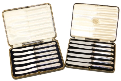 A set of six Edward VII silver handled cake knives, each handle with embossed floral and scroll decoration, stainless steel blades, Sheffield 1902, in fitted case, together with a set of six George V silver handled fruit knives, Sheffield 1934, each in a