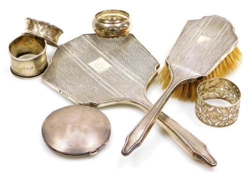 A group of small silver, comprising a George V silver mounted hairbrush and hand mirror, Birmingham 1914, four silver napkin rings, and an engine turned silver compact.