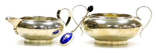 A George V silver two handled sugar bowl and matching cream jug, each of squat rounded form with ribbed rims, on a circular foot, Thomas Bradbury & Sons, Sheffield 1927, 8.68oz, together with an Elizabeth II silver coffee bean spoon, the reverse to the bo