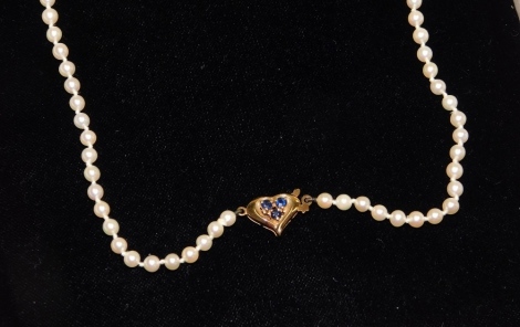 A string of cultured pearls, on a 9ct gold and sapphire set heart shaped clasp, cased.