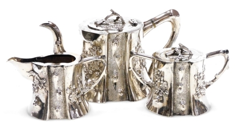 A 19thC Chinese export silver three piece tea set, of naturalistic trunk form, embossed in high and bas relief with prunus blossom, comprising teapot, cream jug and sucrier, marks for Pao Kuang Co, 29.78oz.