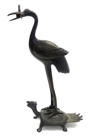 A Japanese bronze candlestick, modelled as a crane on a minogame mythical turtle with hairy tail, lacking candle sconce, 18cm high.