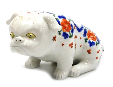 A Japanese Meiji period porcelain figure of a dog, modelled in seated pose, polychrome decorated with flowers and leaves, 18cm wide.