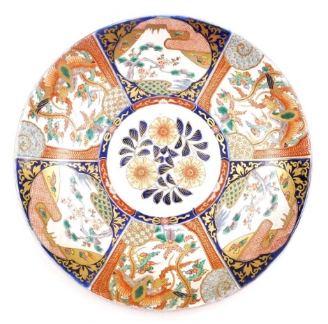 A 19thC Japanese Imari charger, decorated centrally with flowers surrounded by reserves of alternating scenes of a phoenix and tree, 45cm diameter.