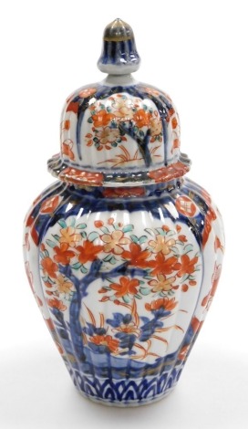 A 19thC Japanese Imari vase and cover, of fluted form, decorated with reserves of flowers and flowering trees, unsigned, 24cm high.