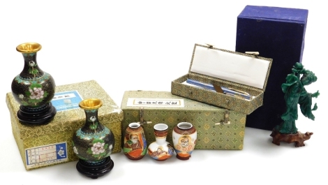 A group of Oriental items, comprising a pair of cloisonne vases, each of baluster form with an elongated neck, decorated with flowers on a black ground, on hardwood bases, 13cm high overall, boxed, a boxed cloisonne fountain and ball point pen set, a set 