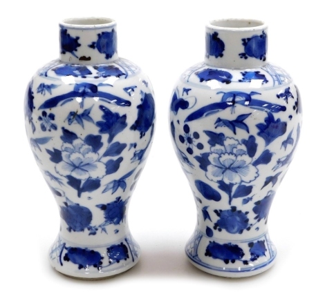 A pair of Qing dynasty blue and white baluster vases, hand painted with flower heads and birds, with underglaze blue four character Kangxi mark, 17cm high.