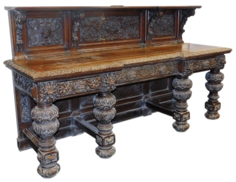 A Victorian oak breakfront sideboard, the shelf topped panelled back carved with masks, fruit and flowers, raised on four scroll supports above one long flanked by two short drawers, with lion's head masks and carved with scrolling leaves, raised on leaf 