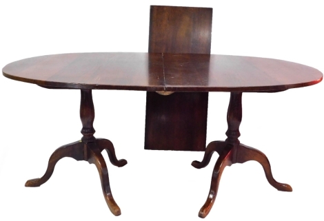 A Georgian style oak twin pedestal dining table, with one additional leaf, raised on baluster turned columns over three cabriole legs, 72cm high, 160cm wide, 206cm extended, 105cm deep.