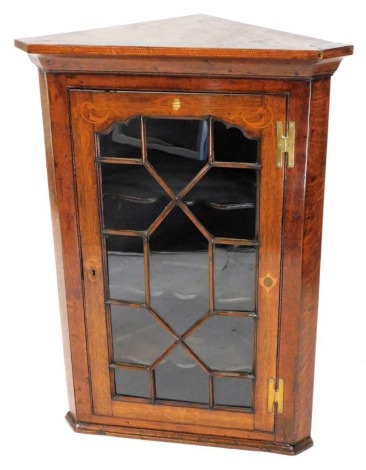 A George III oak hanging corner cabinet, the top with a moulded edge above an astragal glazed door, with inlaid ebony and boxwood cross banding and mother of pearl shaped motifs, enclosing three shaped shelves, 103cm high, 70cm wide, 42cm deep.