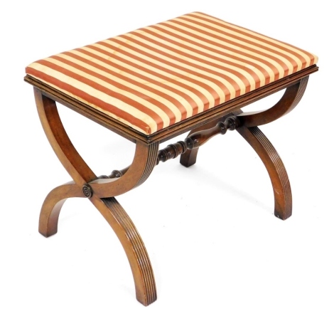 A Regency style mahogany stool, the padded top upholstered in striped fabric with X shaped reeded end supports, and turned stretcher, 57cm wide. The upholstery in this lot does not comply with the 1988 (Fire & Fire Furnishing) Regulations, unless sold to