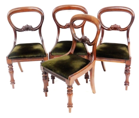 A set of four Victorian mahogany balloon back dining chairs, with carved scroll and centre rails and drop in seat, on turned and fluted legs.