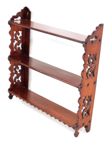 A Victorian mahogany hanging wall shelf, formed with three shelves, with carved scroll end supports, 72cm high, 70cm wide, 16cm deep.