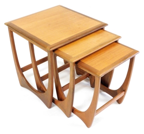 A nest of three G-Plan teak tables, each raised on a U shaped support, the largest 52cm high, 50cm wide, 50cm deep.