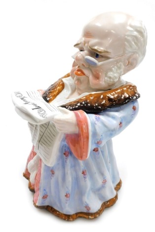 A late 19thC Continental porcelain tobacco jar, modelled as a man seated wearing a smoking jacket and reading The Leeds Mercury, 25cm high. A/F.