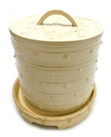 A 19thC creamware cheese dome, of circular form with raised banding and simulated rivets, on a circular base, 27cm high.