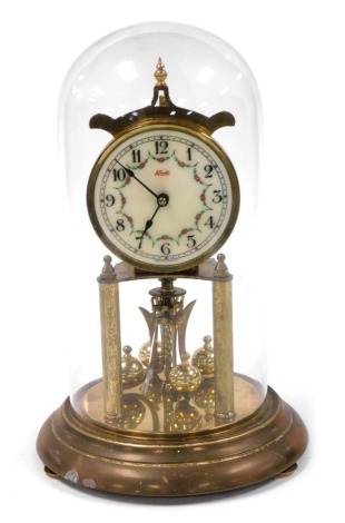 A Kundo brass 400 day anniversary clock, secular enamel dial decorated with floral swags, bearing Roman numerals, on a metal base, with glass dome 31cm high.