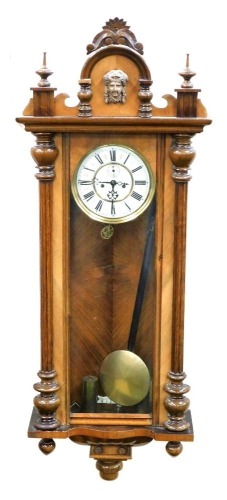 An early 20thC walnut cased Vienna wall clock, the enamel dial bearing Roman numerals, subsidiary seconds dial and brass chapter ring, with weights and pendulum, 134cm high.