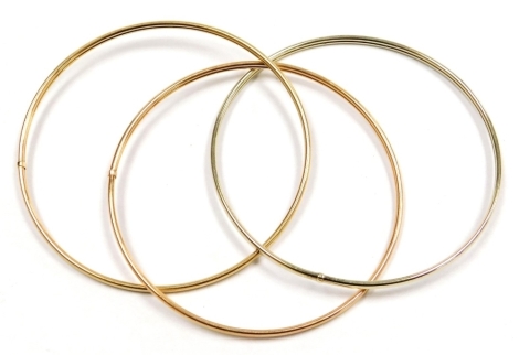 A 9ct three colour gold interlinked triple bangle, 10.4g.