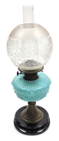 A late 19thC oil lamp, with a clear and etched glass globular shade, with a blue vaseline glass central reservoir, raised on a brass support on a black socle base, with chimney, 59cm high.