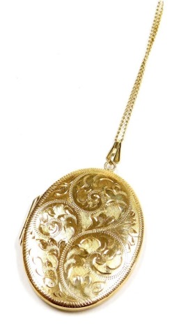 A 9ct gold oval photo locket, with foliate engraving, on a curb link neck chain, with bolt ring clasp, stamped 9ct, 12.9g.