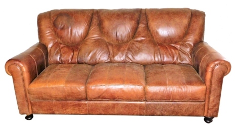 A tan leather three seater sofa, with loose cushion seats and scrolling arms, 194cm wide.