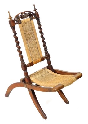 A Victorian beech and cane folding child's chair, with a foliate carved crest rail, cane seat and back, raised on curved legs.