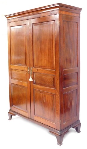 An early 20thC mahogany armoire, the pediment over a pair of panelled doors, opening to reveal a brass hanging rail, raised on a plinth base and bracket feet, 201cm high, 134cm wide, 56cm deep.