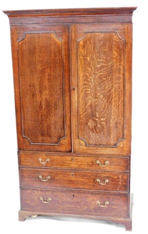 A George III oak linen press, converted to a wardrobe, the out swept pediment over a pair of panelled doors over two dummy and one long drawer, raised on bracket feet, 194.5cm high, 112cm wide, 58cm deep.