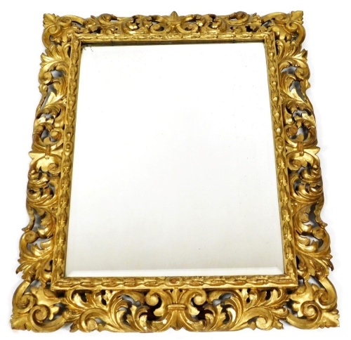 A 19thC giltwood wall mirror, with later strut to back, the rectangular bevelled plate within a carved foliate surround, 92cm high, 74cm wide.