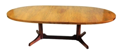 A 1970s rosewood oval dining table, with extending action and additional leaf, raised on two plain column supports and flat profile legs and centre stretcher, 73cm high, 202cm wide (unextended), 110cm deep.